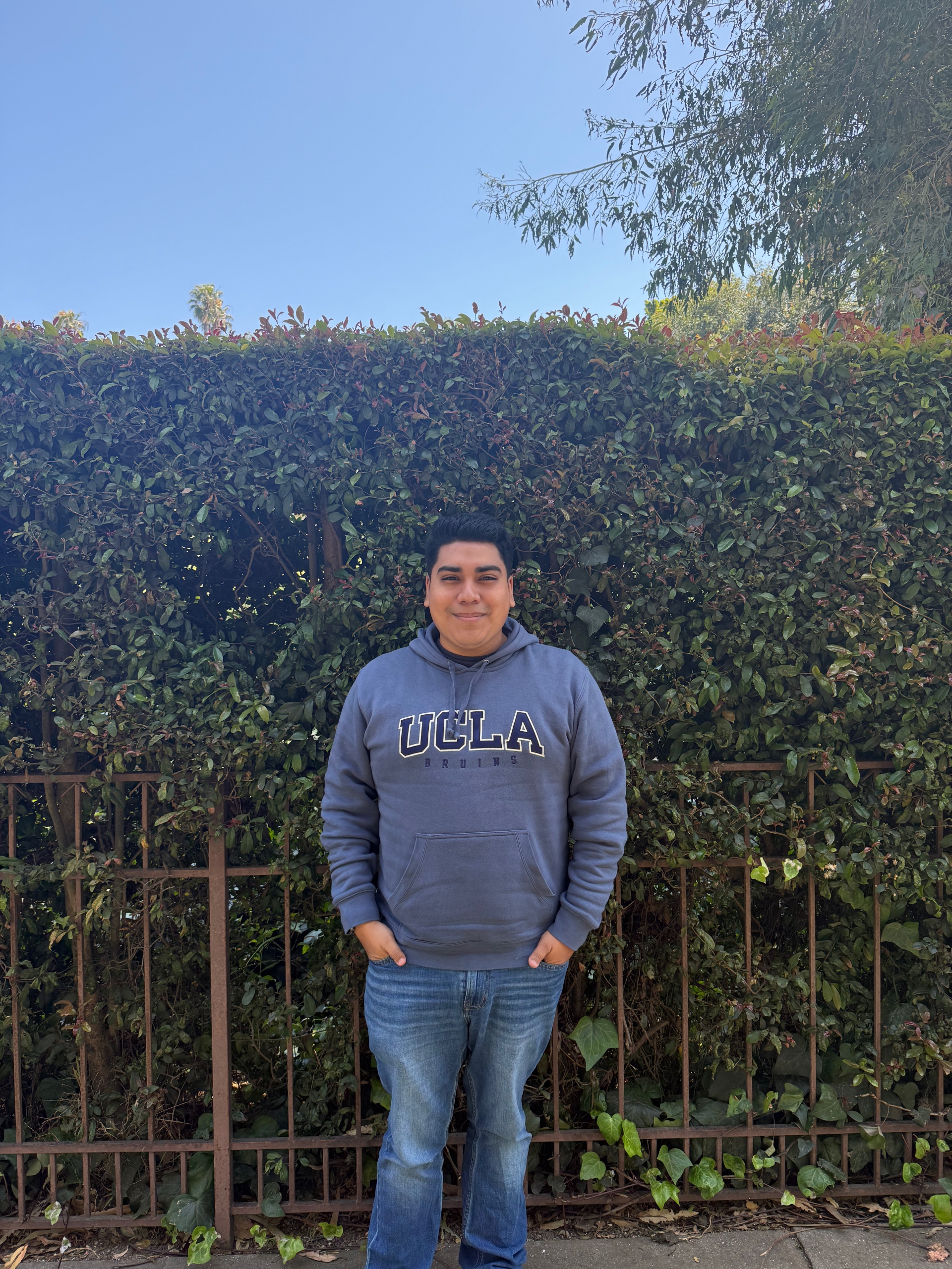 Gio standing in front of a leaf wall