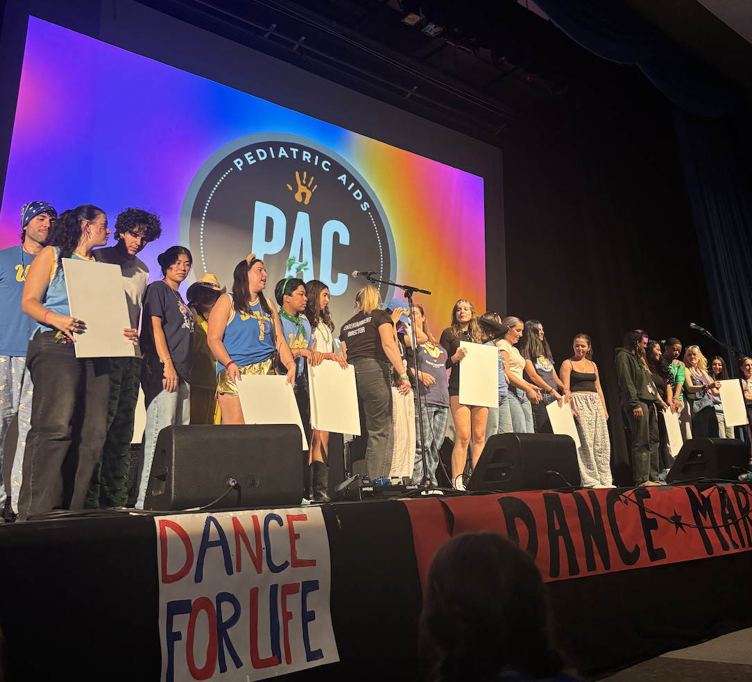 A crowd of people on stage supporting dance communities and those affected by pediatric aids.
